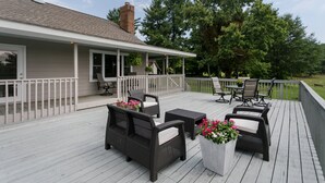 A covered deck with wicker furniture and potted plants. - Oak Knob Equestrian Home (Campobello)