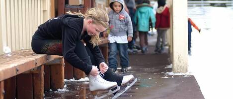 A person adjusting a pair of ice skates on a bench.