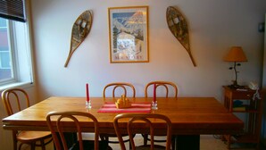 Une salle à manger avec une table en bois, quatre chaises, un tableau encadré au mur et une lampe sur une table d’appoint.