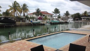 A swimming pool with a view of a marina and houses in the background. - Compelling Canal Home with Pool & Large Dock on each side-Cabana Club Included (Key Colony Beach)