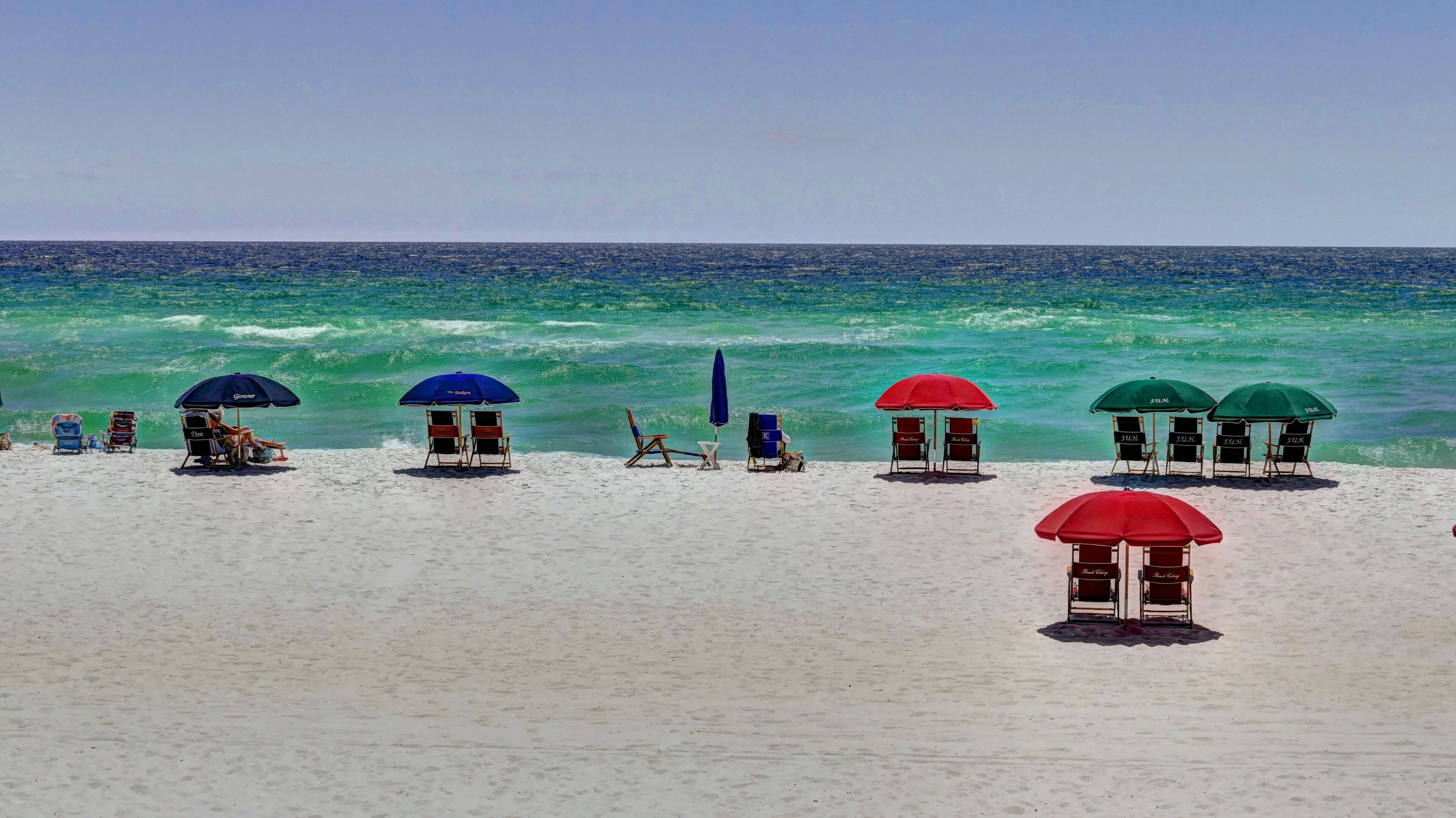 A beach with multiple sun umbrellas and beach chairs.