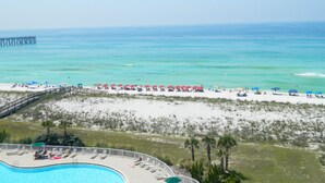 A beach resort with a swimming pool, beach umbrellas, and a pier in the background. - Fabulous condo, excellent reviews!! 2 chairs and 1 umbrella (Available Mar-Oct) (Navarre)