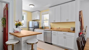 A modern kitchen with white cabinets, stainless steel appliances, and a wooden countertop. - Dog Friendly with Hot Tub - Alpine Adventure (Red Lodge)