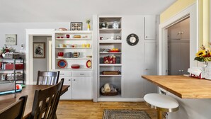 A kitchen with white cabinetry, a wooden dining table, and a built-in shelf unit with various dishes and decorations. - Dog Friendly with Hot Tub - Alpine Adventure (Red Lodge)