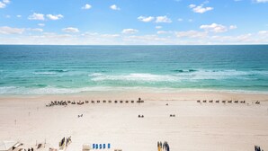 A beach with a wide sandy area, a few umbrellas, and people scattered across the sand.