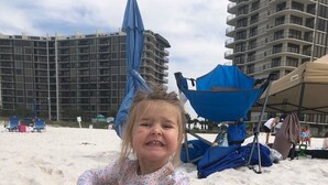 A child playing with sand toys on a beach with buildings in the background. - Wow!Beachfront Paradise 2BR 2BA+Bunks book now for Fall and Winter! (Panama City Beach)