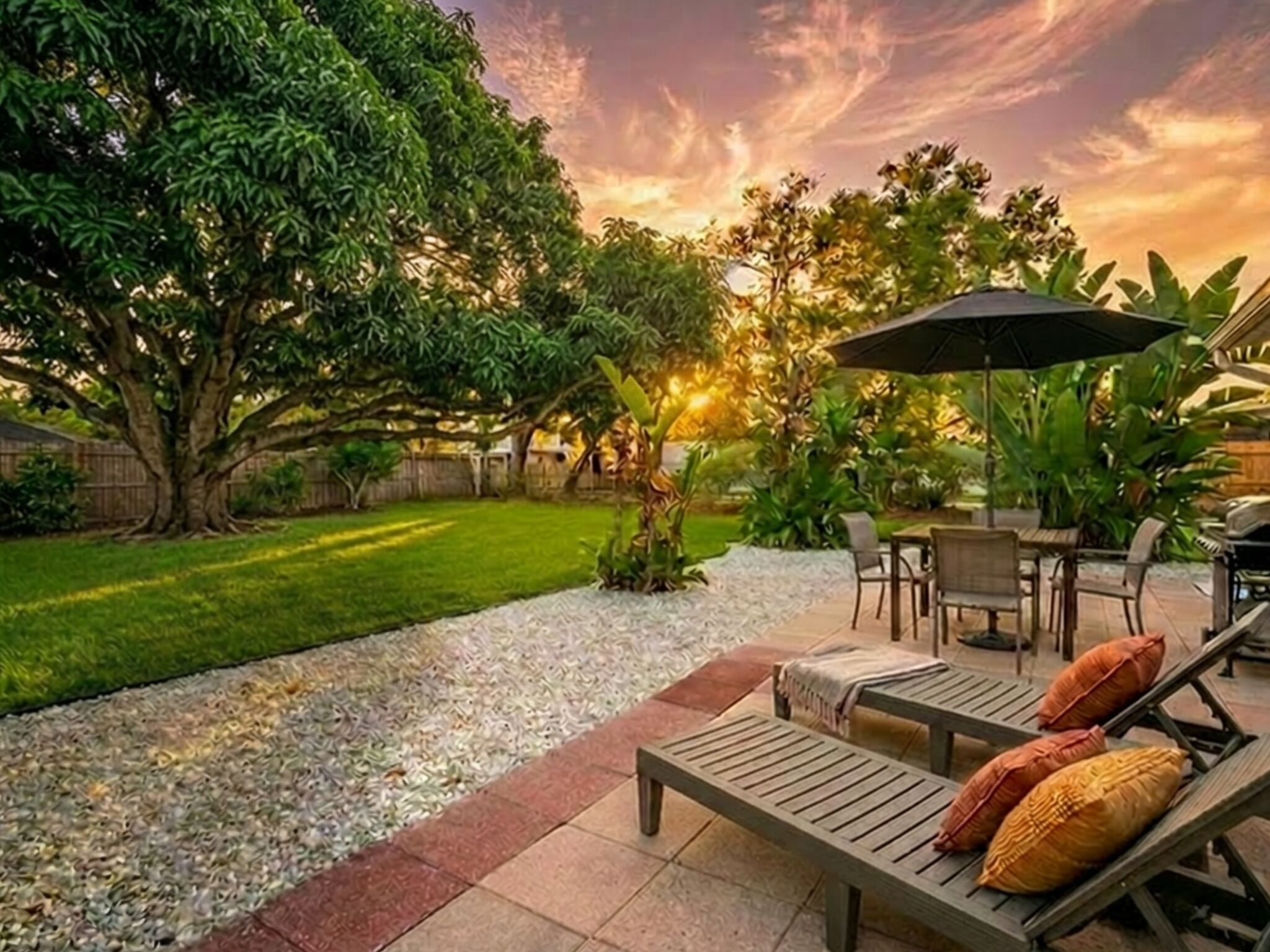 Un patio con mesa y sillas, una parrilla y un árbol.