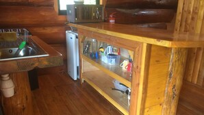 Eine Holzhüttenküche mit Spüle, Mikrowelle und Kühlschrank.