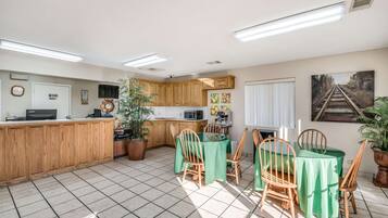 Una habitación amplia y bien iluminada con zona de cocina, una mesa de comedor con sillas y un mostrador de recepción.