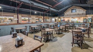A restaurant with multiple tables and chairs, a counter with a menu, and a rustic wooden structure in the background. - Rodeway Inn Gurdon I-30 (Gurdon)