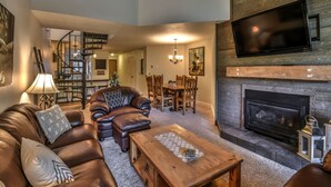 A spacious living room with a fireplace, leather sofa, and a dining area with wooden chairs. - Breckenridge Peak 8 updated Ski in condo (Breckenridge)