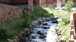 A small stream flowing through a landscaped area with a stone wall and a wooden bench. - Breckenridge Peak 8 updated Ski in condo (Breckenridge)