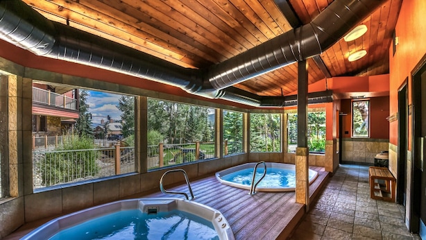 A spa area with two hot tubs, wooden flooring, and large windows offering views of the outdoors. - Breckenridge Peak 8 updated Ski in condo (Breckenridge)