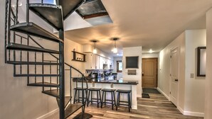 A modern kitchen with a central island, bar stools, and a spiral staircase. - Breckenridge Peak 8 updated Ski in condo (Breckenridge)