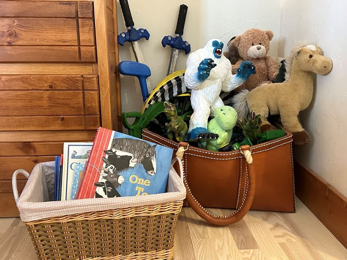 Ein Korbbusch und eine Lederstasche, gefüllt mit Büchern und Stofftieren.