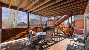 A wooden deck with a table and chairs, a staircase, and a view of trees and buildings. - Mountain View Tee and Ski (Red Lodge)