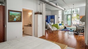 Un dormitorio moderno con una cama grande, un baño con ducha y vistas al área de estar.