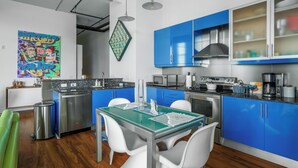 Una cocina moderna con armarios azules, electrodomésticos de acero inoxidable y un comedor con sillas blancas.