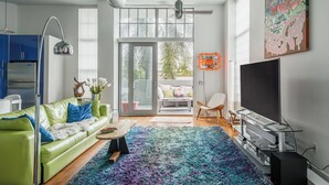 Una sala de estar moderna con un sofá verde, una mesa de centro, un televisor de pantalla plana y una alfombra colorida.