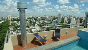 Une piscine sur le toit, avec deux chaises longues et une vue sur le paysage urbain.
