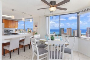 A modern kitchen with a large island, white chairs, and a dining table set for four. - 2bed/2bath Penthouse Ocean View...Recent Luxurious Renovation (Honolulu)
