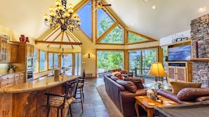 A spacious kitchen with a large island, wooden cabinets, and a chandelier.