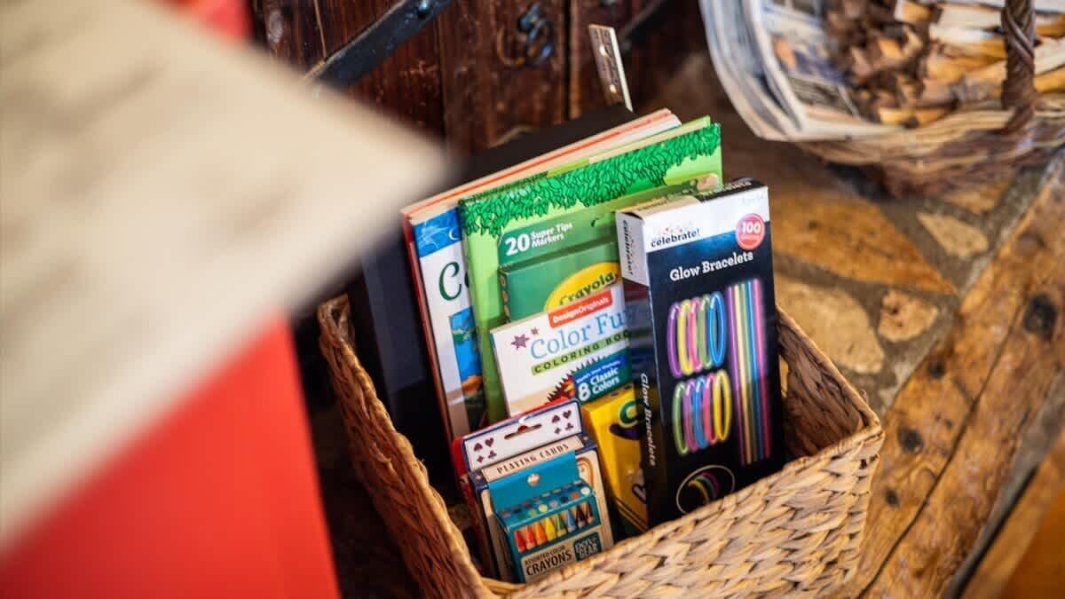Ein Korb voller verschiedener Bastelutensilien, darunter Buntstifte, Filzstifte und Malbücher.