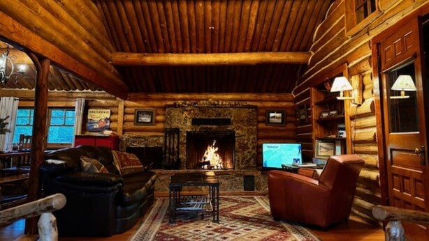 A log cabin interior with a fireplace, leather furniture, and wooden walls. - Rendezvous Lodge (Red Lodge)