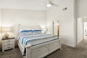 A bedroom with a bed, nightstand, lamp, and ceiling fan.