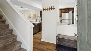 A modern kitchen with white cabinetry, a stainless steel refrigerator, and a wooden staircase. - 307 Sailmaker in Summer Beach (Fernandina Beach)