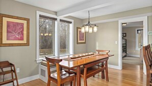 A dining area with a wooden table and chairs, framed artwork on the walls, and a chandelier. - Tight Lines (Red Lodge)