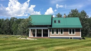 A two-story house with a green roof, a covered porch, and a well-maintained lawn. - Tight Lines (Red Lodge)
