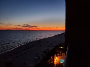 Ein Strand bei Sonnenuntergang mit einem Poolbereich im Vordergrund.