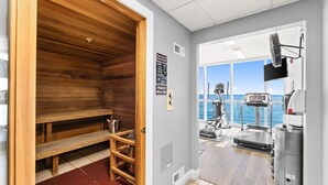 Una sauna con bancos de madera, una cinta de correr y vistas al mar.