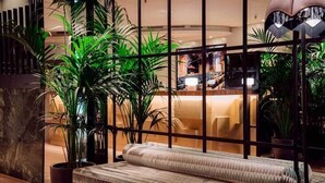 A modern interior with a sofa, potted plants, and a reception area.