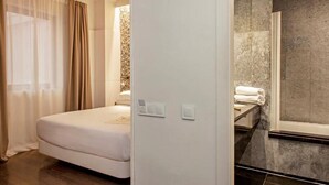 A hotel room with a bed, a bathroom with a bathtub, and a shower. - Chic and Basic Velvet (Barcelona)