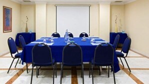 A conference room with a long table, blue chairs, and a projector screen. - Chic and Basic Velvet (Barcelona)