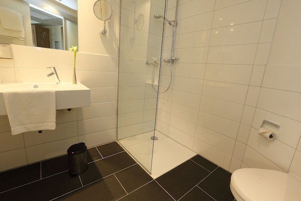 Un baño moderno con ducha de vidrio, un lavabo con toalla y un inodoro.