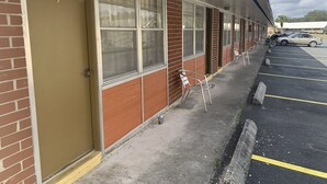 Una hilera de habitaciones con ventanas amplias, fachada de ladrillo y un estacionamiento con un automóvil y una motocicleta.