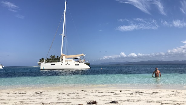 A sailboat on calm waters near a beach with clear skies. - iCan Sailing Experience (Turneffe Islands)