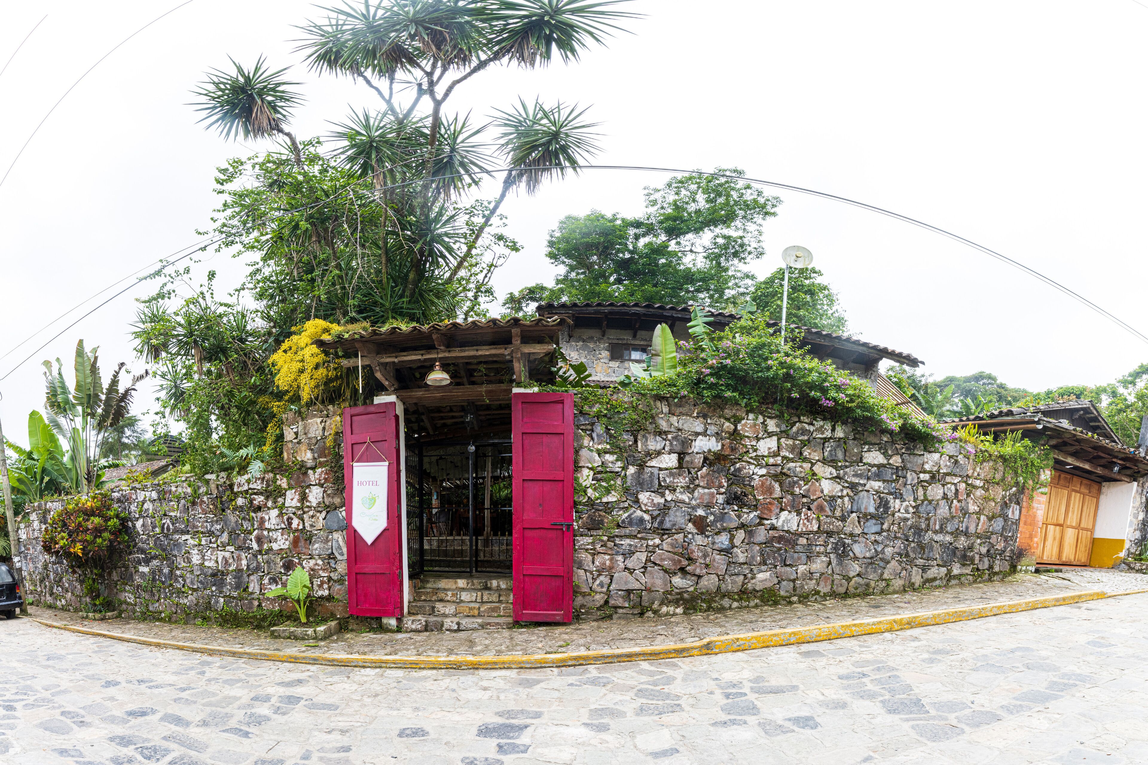 Un edificio de piedra con techo de madera, una puerta roja y un cartel que indica que es un hotel.