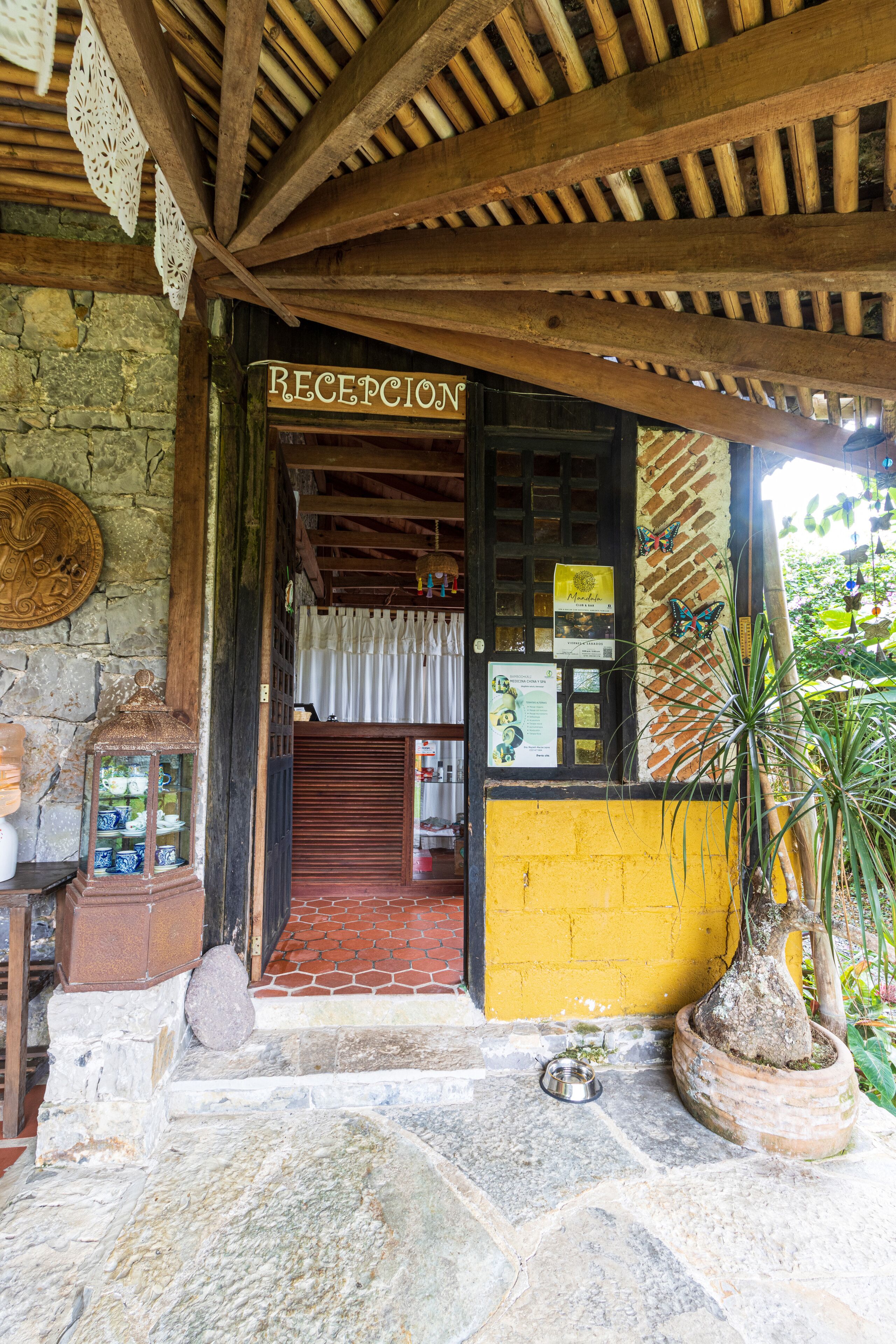 A reception area with a wooden ceiling, a brick wall, and a yellow door.