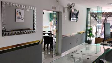 A reception area with a glass counter, a fan, and a sign with a logo.