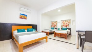 A hotel room with a large bed, two smaller beds, a desk, and a chair. - Ayenda Zhena (San José de Cúcuta)
