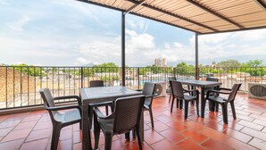 A covered outdoor patio with a table and chairs, a view of buildings and mountains in the distance. - Ayenda Zhena (San José de Cúcuta)