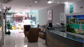A reception area with a glass counter, seating, and a view of the street. - Ayenda Zhena (San José de Cúcuta)
