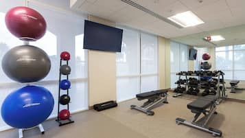 Une salle de sport équipée de matériel d’exercice, d’un téléviseur et dotée de grandes fenêtres.