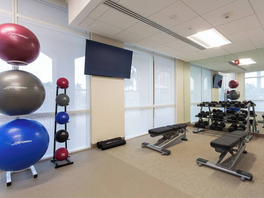 Une salle de sport équipée de matériel d’exercice, d’un téléviseur et dotée de grandes fenêtres.