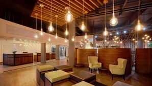 A spacious lobby with wooden flooring, multiple seating areas, and hanging pendant lights. - Protea Hotel by Marriott Pretoria Loftus Park (Pretoria)