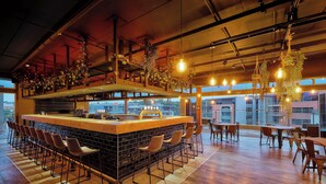A modern bar area with a long counter, multiple stools, and hanging light fixtures. - Protea Hotel by Marriott Pretoria Loftus Park (Pretoria)